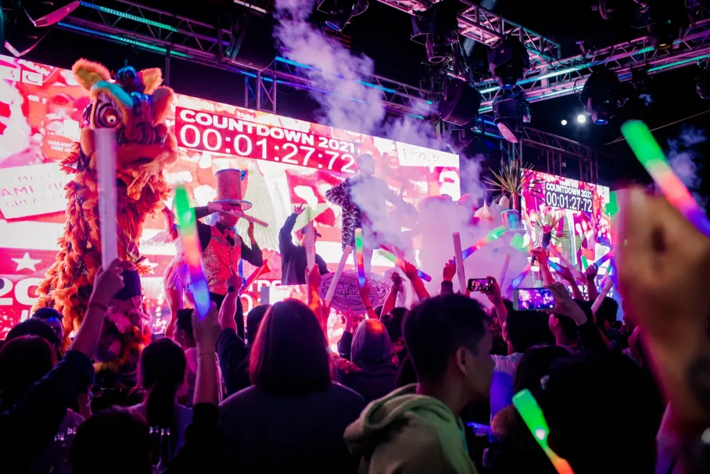 New Year's Eve in Nha Trang at Skylight: crowd waving glow sticks at the countdown, with a lion dance and countdown screen on stage