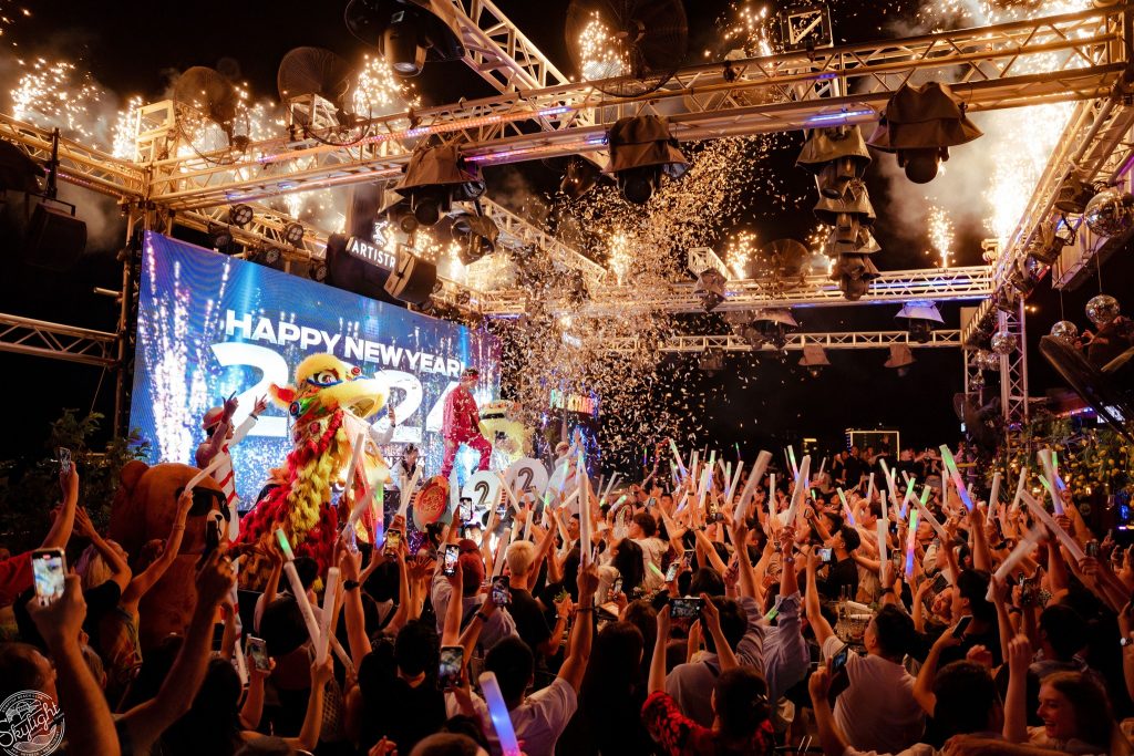 Happy New Year stage with a lion dance, cold sparklers and confetti at Skylight Nha Trang, guests raising glow sticks